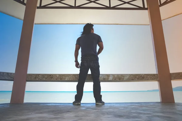 Bir Asya adam stand çevirmek çatı altında sırt yanında gelen tekne bekliyorum deniz