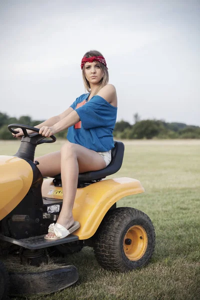 Working girl driving a lawn mower — Stock Photo, Image