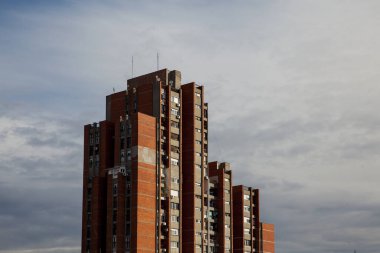 Mavi gökyüzüne karşı kırmızı cepheli bir grup bina.