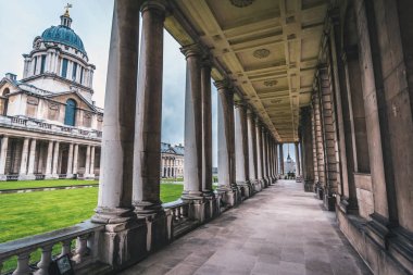 Londra, İngiltere - Mart, 2016: kararsız Greenwich Üniversitesi bulutlu bir günde sütunlar arasında oturan genç kadın.