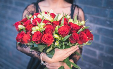 woman holding in hands bunch of red roses, crop