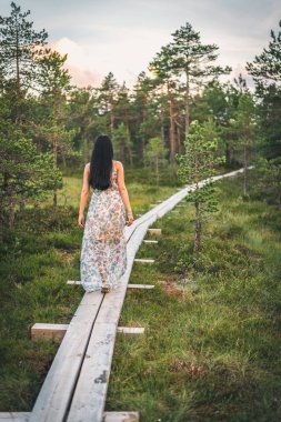 Elbise yalnız günbatımına ahşap yolu ormandaki yürüyüş yalnız genç kadın