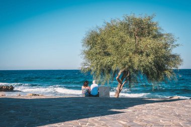 Kıbrıs'ta sahilde yeşil ağacın altında oturan Romantik Çift