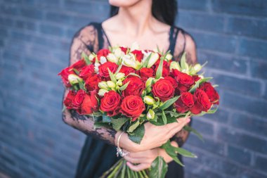woman holding in hands bunch of red roses, crop