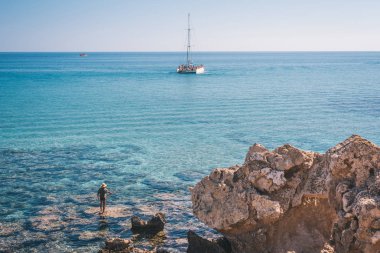 Tropikal rock plaj ile berrak turkuaz su, deniz ve white yat üzerinde göster