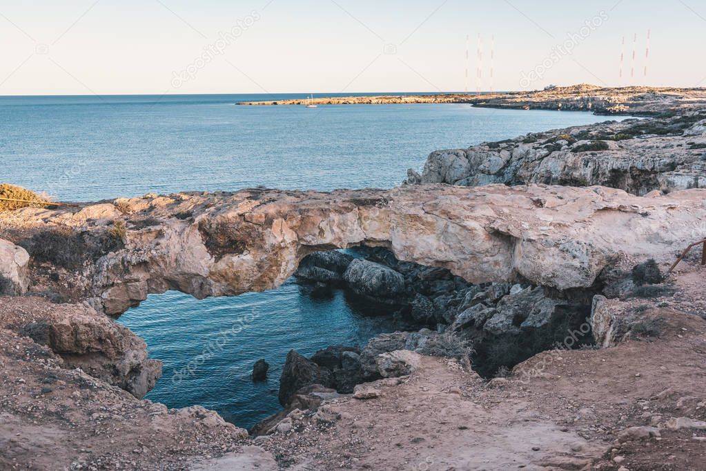 Nature-made rock bridge in Cyprus with view over blue sea