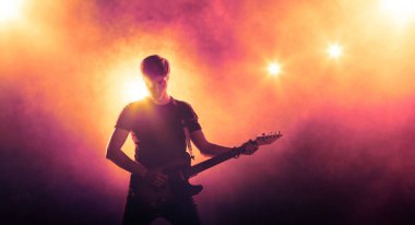 Sahnede sahne ışıkları altında gitarist silueti. Müzik konseri