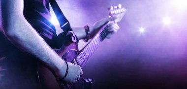 Spot ışığında gitar çalan bir adam. Müzik performansı