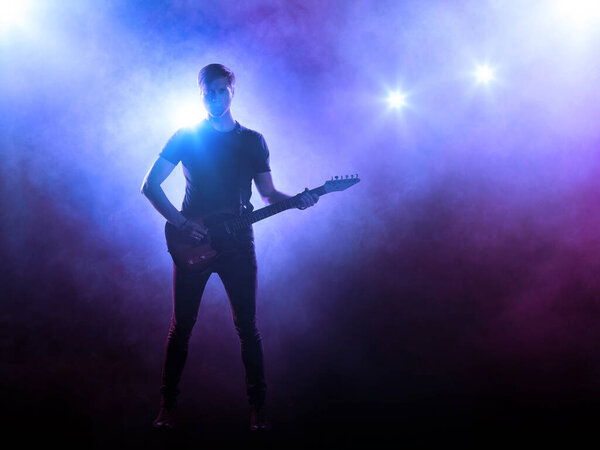 Silhouette of guitar player on stage in spotlight. Music concert