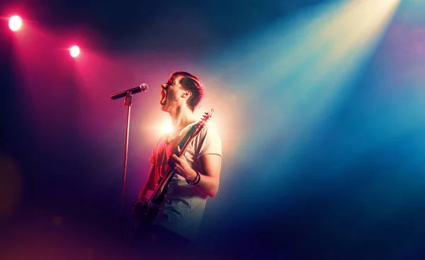 ステージ上でマイクで歌うギター奏者 — ストック写真