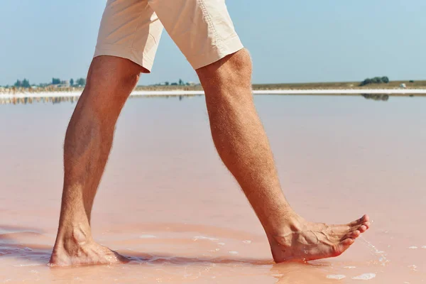 Jambes de l'homme et le lac salé rose Photo De Stock