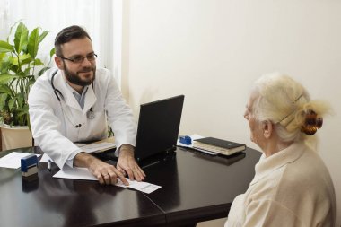 Doktor hastanın tıbbi geçmişini yazma bir parmağını gösterir.