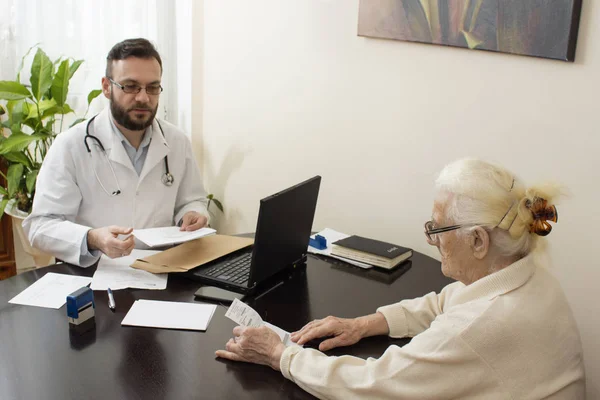 Um médico mostra um dedo escrevendo na história médica do paciente . — Fotografia de Stock