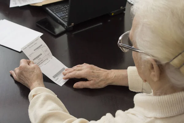 Mulher velha segura em suas mãos uma receita e lê — Fotografia de Stock