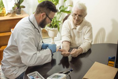 Özel bir doktor ofisi. Yaşlı bir kadının el inceleyerek doktor.