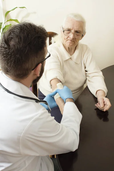 Un cabinet de médecin privé. Docteur examinant la main d'une vieille femme . — Photo