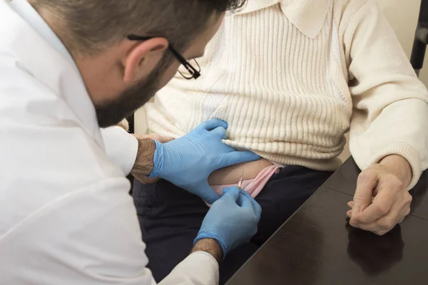 Un médico le da una inyección en el vientre de una anciana . — Foto de Stock