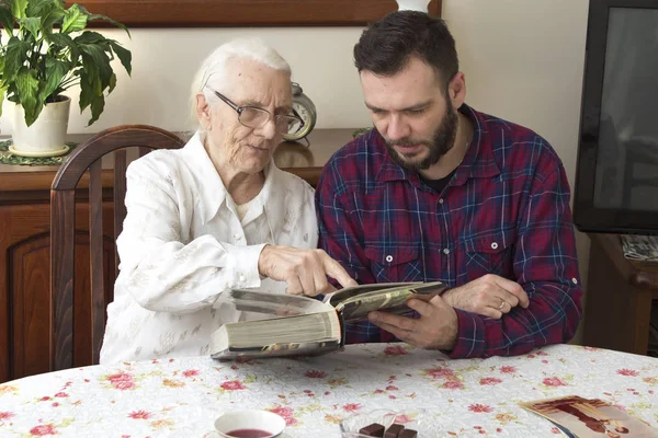 Abuela con nieto recordar los viejos tiempos viendo álbum de fotos . — Foto de Stock