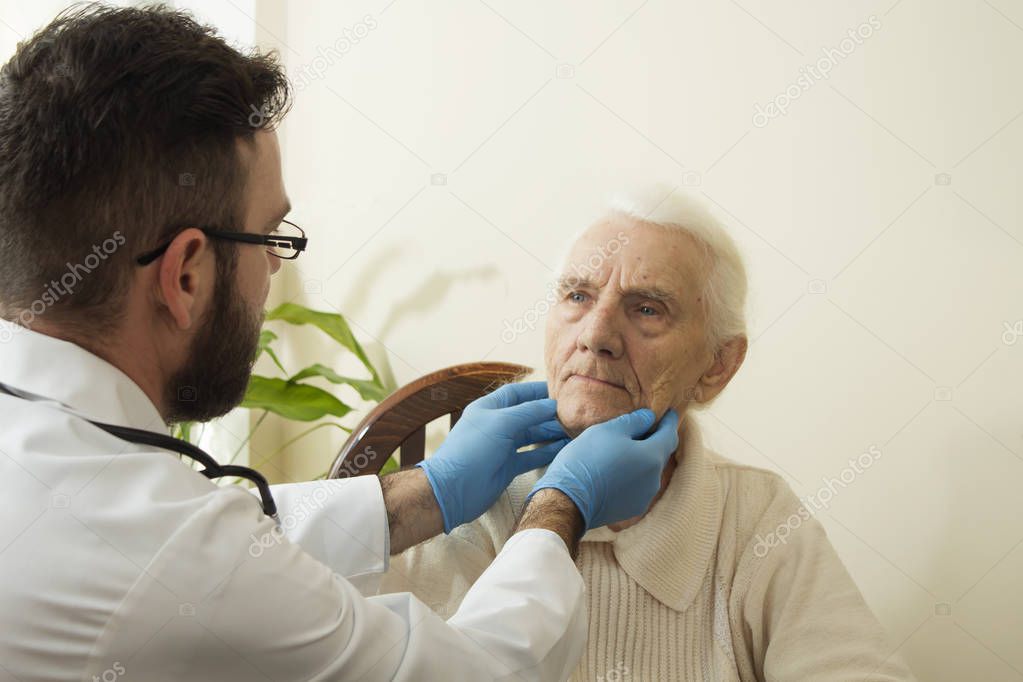 The doctor examines the lymph nodes on the neck of an old woman. 