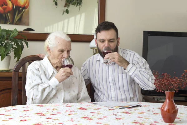 Avó com neto sentado à mesa e brinde. Segurando um copo de vinho tinto . — Fotografia de Stock