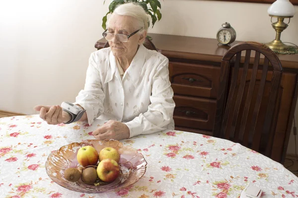 La anciana mide la muñeca del aparato de presión . — Foto de Stock