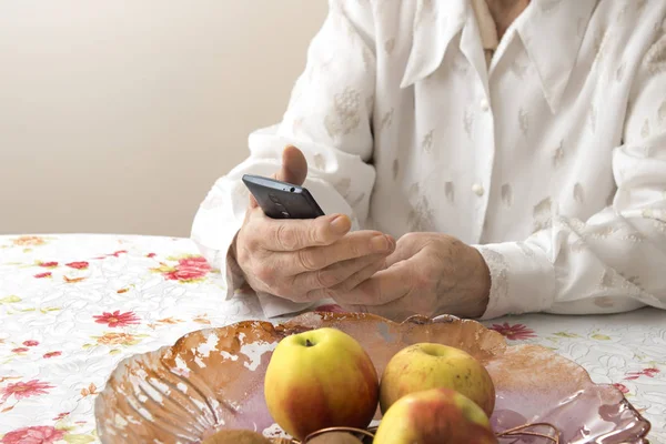 Manos de una anciana sosteniendo un teléfono móvil . — Foto de Stock