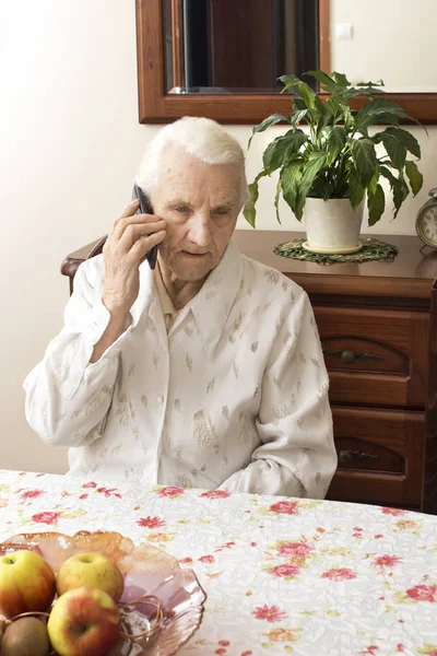 Manos de una anciana sosteniendo un teléfono móvil . — Foto de Stock