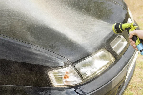 Flushing the car body with water from a garden hose.