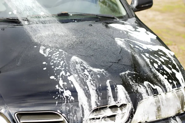 Flushing the car body with water from a garden hose.