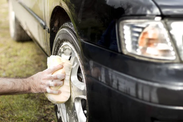 Man tvättar en bil svamp med en aluminiumlegering bil schampo. — Stockfoto