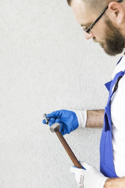 Τα χέρια του εργάτης οικοδομών στα προστατευτικά γάντια αποδίδουν το μπουλόνι άγκυρα στον τοίχο του κτιρίου. — Φωτογραφία Αρχείου