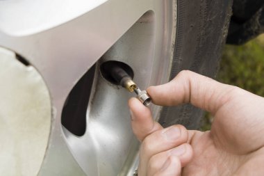 Rka mechanika odkrca maszynk wentyla w kole samochodu.