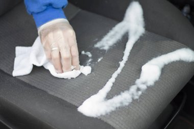 Tek kullanımlık eldiven elinde tutmak araba koltuk koltuk yıkamak için beyaz bir bez .