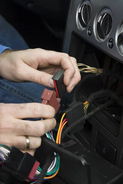 The mechanic hooks the cube with the wires to the car\'s electrical system