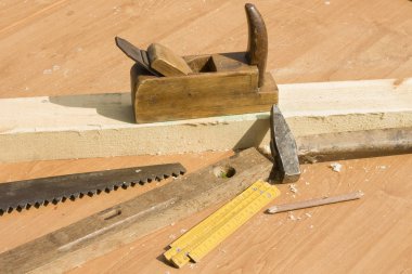 El uçak. Bir çalışan uçak kurulu. Eski marangoz araçları masanın üstüne yalan. Uçak, testere, seviye, kepçe, çekiç, kalem,