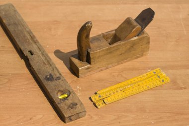 Eski marangoz araçları masanın üstüne yalan. Uçak, testere, seviye, kepçe, çekiç, kalem,