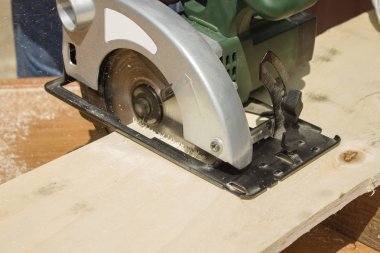 İnşaat işçisi bir tahta bir daire testere ile geçer. Marangoz kurulu elektrikli testere kullanarak bölü. Marangoz atölyesi. Marangoz Osb keser