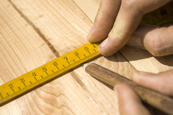 Marking distances. The carpenter's hands measure distance measure.