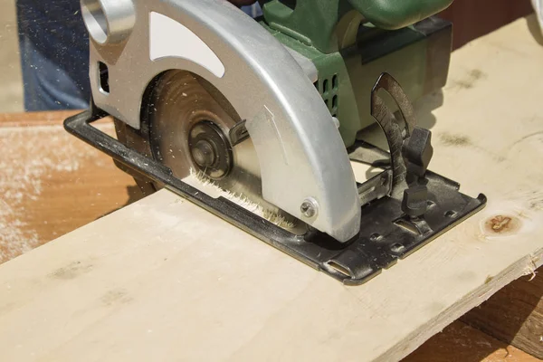 İnşaat işçisi bir tahta bir daire testere ile geçer. Marangoz kurulu elektrikli testere kullanarak bölü. Marangoz atölyesi. Marangoz Osb keser