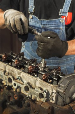 Tamircinin eli soket anahtarı ile motordaki vidayı söküyor. Vana musluklarını ve şaftı sökmek. Eski bir motorun içi..