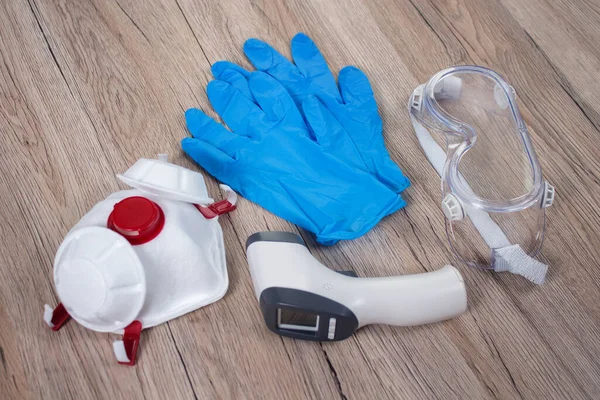 Koruyucu maske, tek kullanımlık eldivenler, elektronik termometre, koruyucu gözlükler. Virüs enfeksiyonuna karşı korunacak eşyalar tezgahta yatıyor..