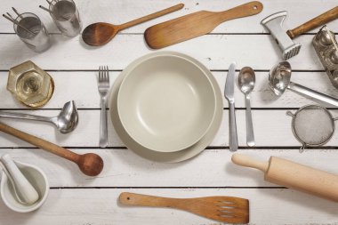 Beyaz tahtalardan yapılmış ahşap bir masada hazırlanan tek kişilik yer. Eski moda mutfak aletleri etrafa saçılmış. Tüm bunlar ilginç bir arkaplan oluşturuyor..