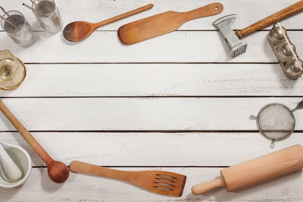 Wooden kitchen utensils form a background. They lie on boards painted white. Background arranged from old stylish kitchen utensils lie on white boards arranged in compositions.