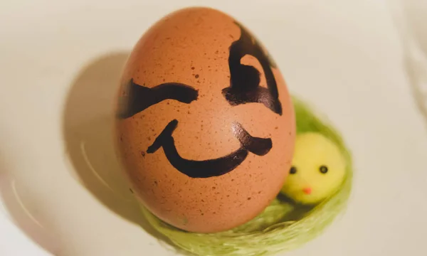 Winking female face expression drawn on the easter egg. Celebration and egg hunting concept.