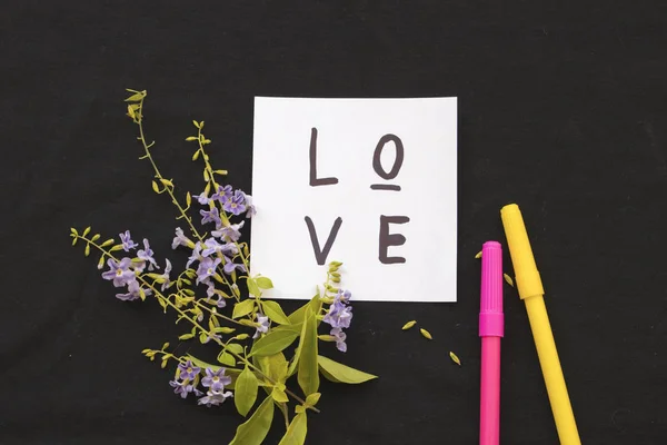 Láska zprávy karta a fialové květy na černém pozadí — Stock fotografie