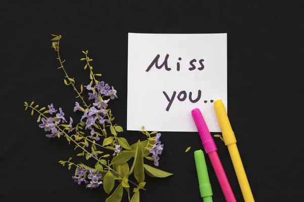 miss you message card and purple flowers on black