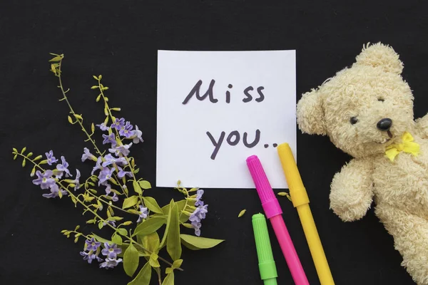 miss you message card and purple flowers with teddy bear on black