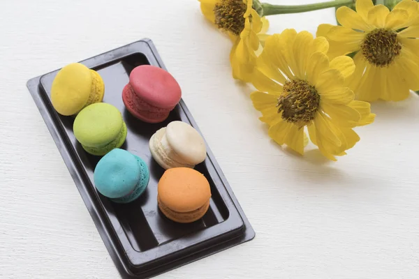 Colorful dessert macaroon and yellow flower on table white — Stock Photo, Image