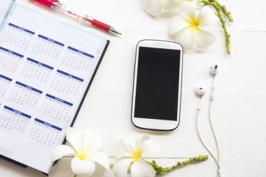 defter planlayıcısı takvim telefon kulaklık ile iş ve Ofis Masası beyaz arka plan üzerinde beyaz çiçek frangipani için