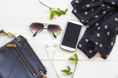 Cep telefonu, omuz çantası, siyah eşarp ve güneş gözlüğü yaşam tarzı aksesuarları.